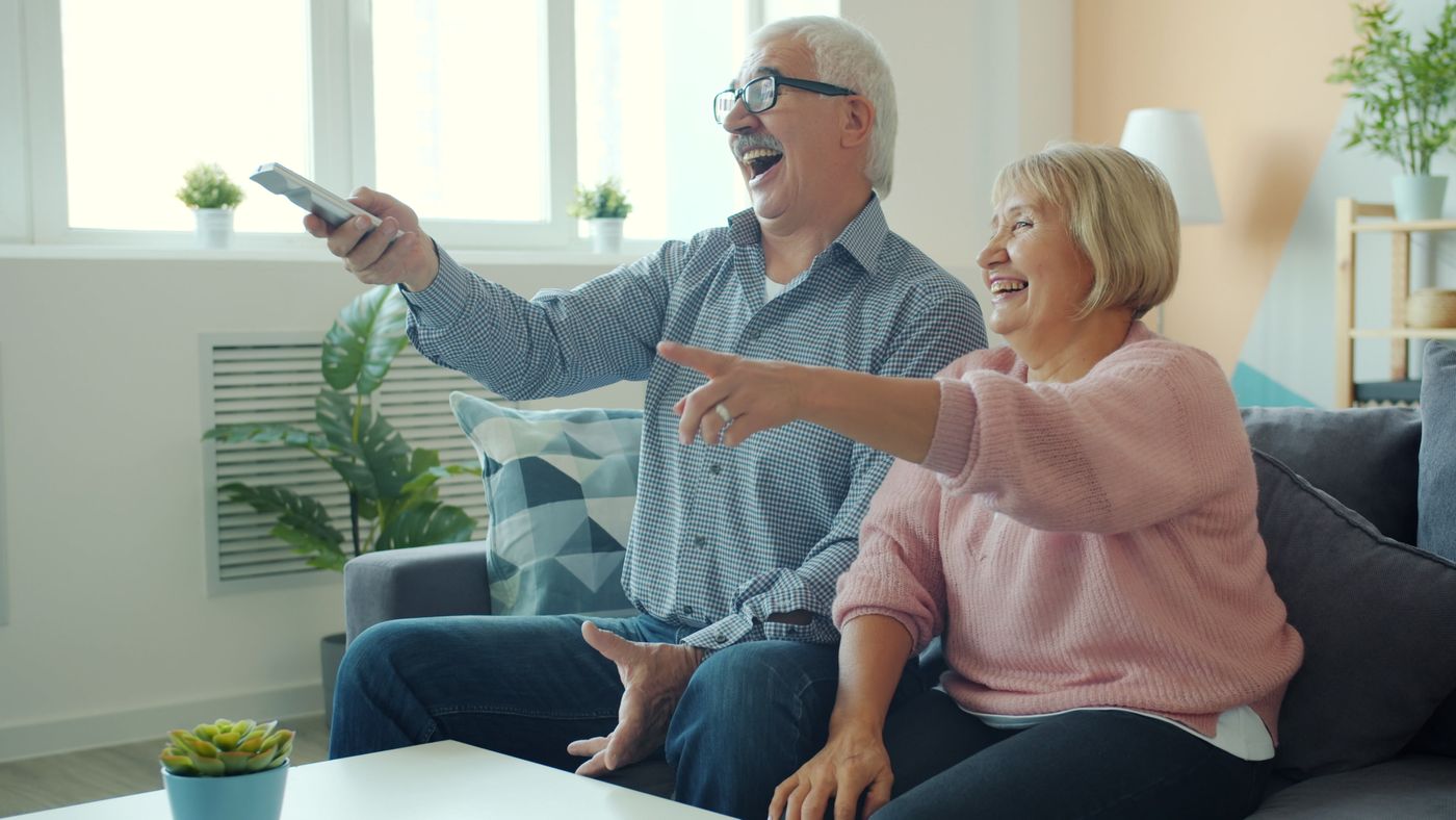 An older couple watching a home video together by the ocean